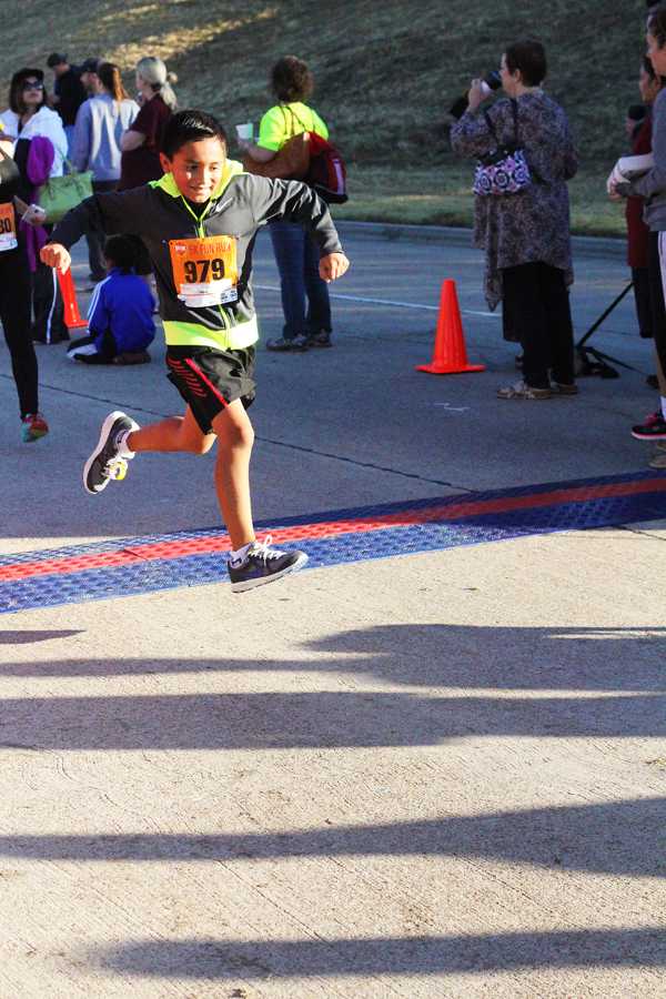 A young runner passes through the finish line.