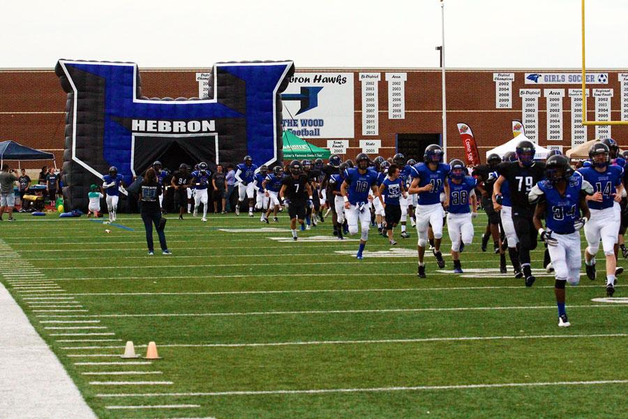 Football players run out of the Super H as the game begins. 