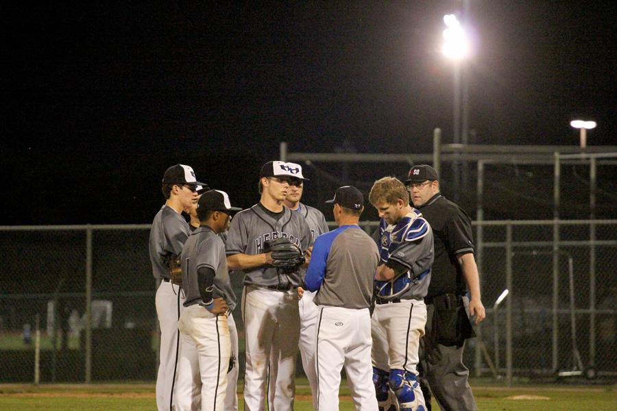 Head coach Steve Stone and the rest of the Hebron infield meet on the mound in the third inning to discuss defensive positioning. Deloach ran into trouble, giving up two runs on a ringing double and subsequent throwing error.