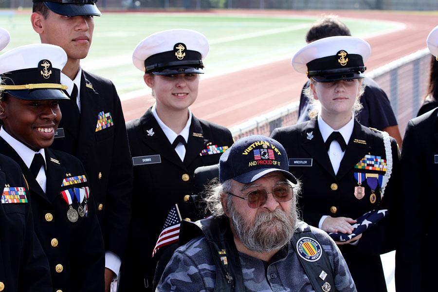 A Vietnam War veteran poses with JROTC after the assembly. The veteran lost both his legs in the war.