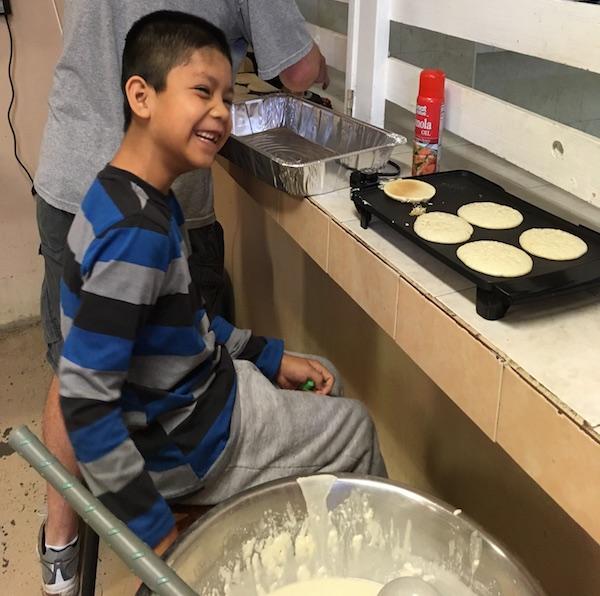 Angel, a resident at Casa Hogar, helps make pancakes for breakfast.
