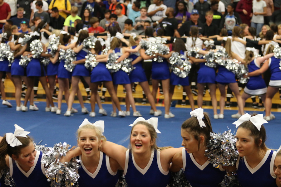 Cheerleaders lead the school in a chant for the football team. They were preparing the crowd for the entrance of the team.