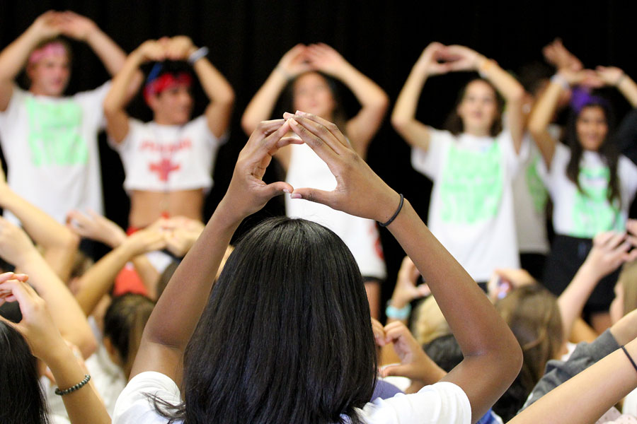 A student council member imitates the officers. The officers were leading the audience in the baby shark game.