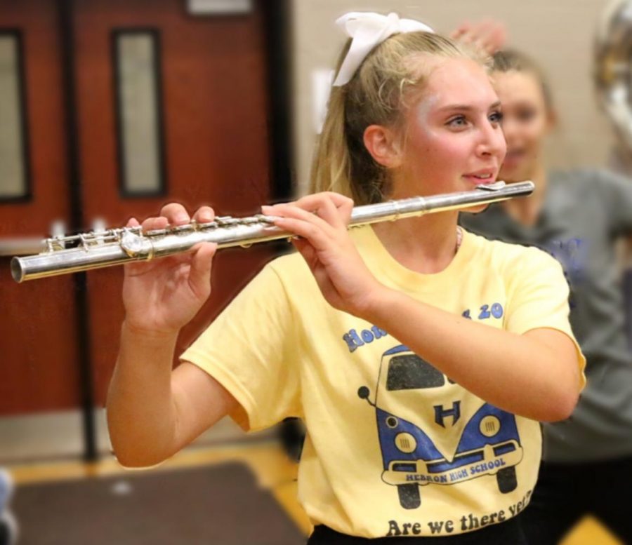 Freshman Jacquelyn Burrer plays the flute at the Homecoming pep rally. During pep rallies, Burrer has to switch from her cheer routine to her position in band. 