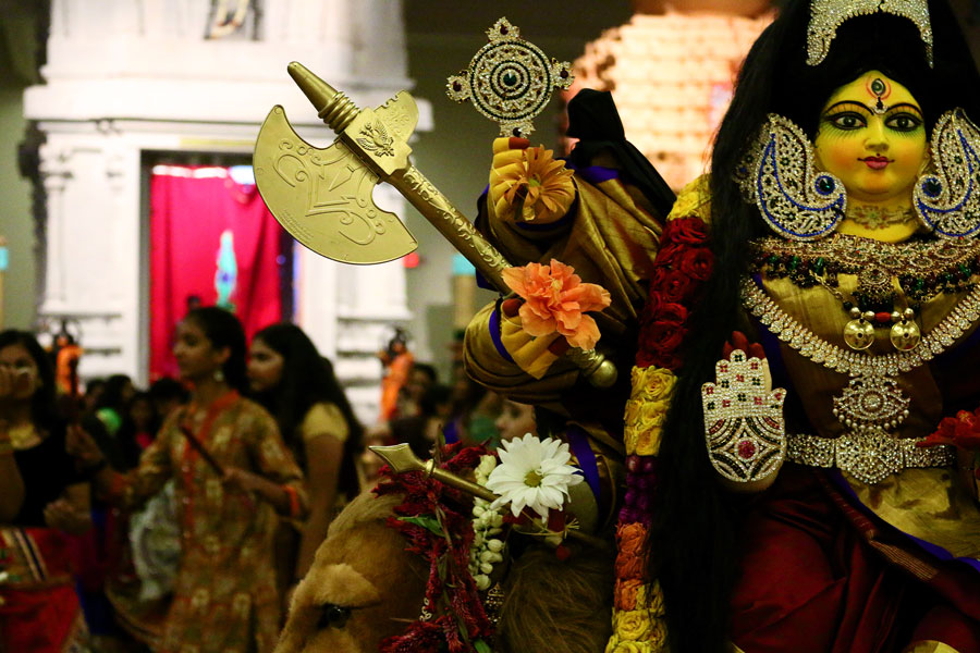 People dance around goddess Durga, goddess of war, during Garba. Goddess Durga is draped in fine clothing and jewelry. 