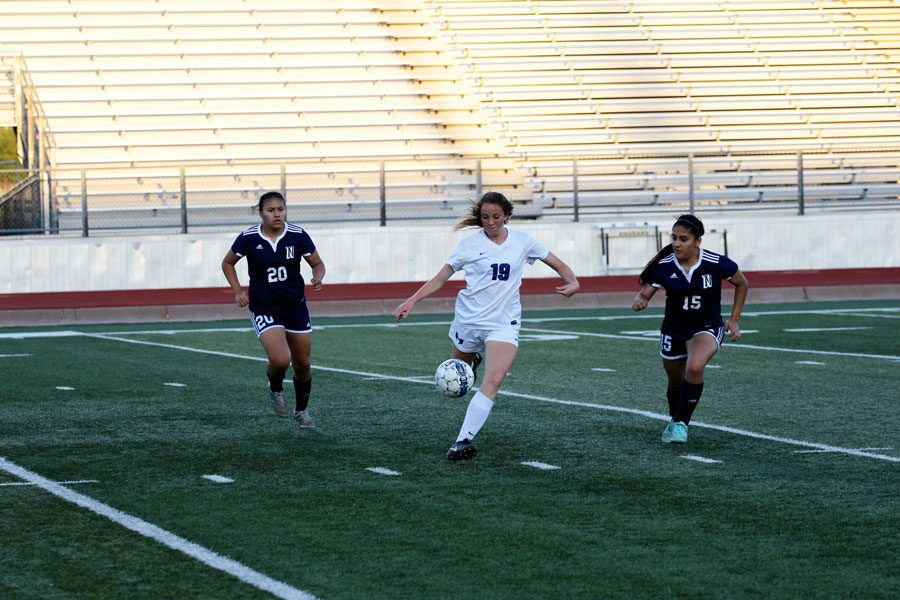 In the playoffs from last year, current junior Abby Glockzin dribbles between two opponents.