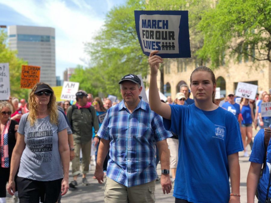 Teen holds March for our Lives poster during the march, followed by many people in support of stopping gun violence.