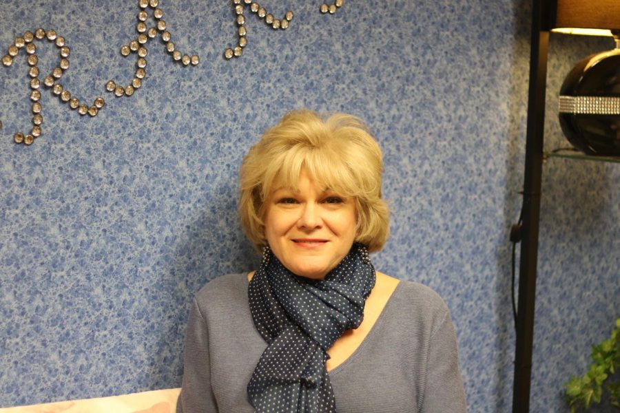 Librarian Liz Harrison poses on her couch within her office. 