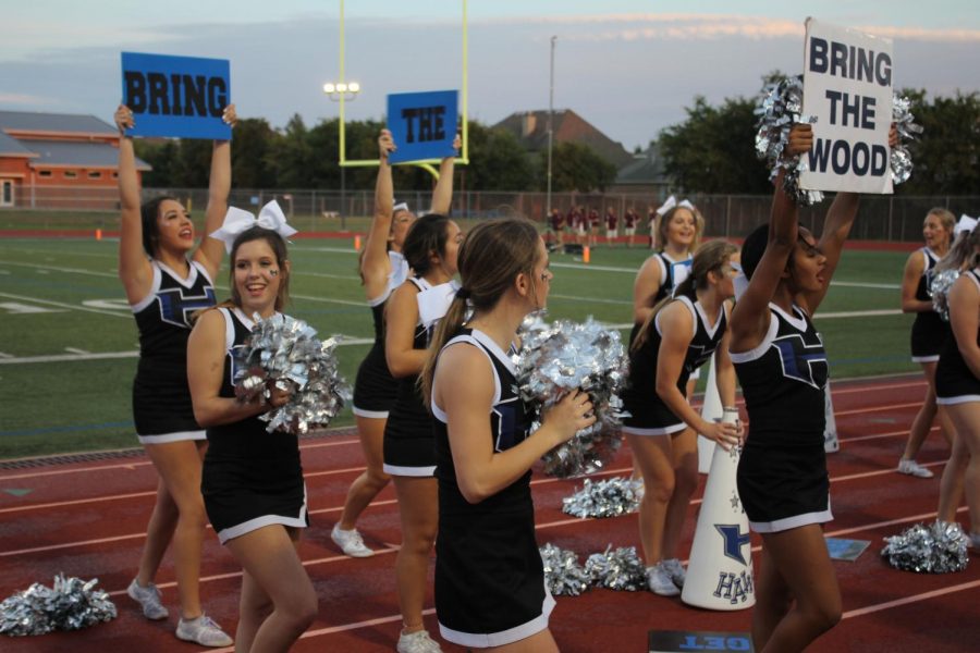 The cheerleaders motivate the crowd to cheer louder and “bring the wood.” They are there to motivate the audience and the football players by yelling, cheering, and performing stunts for the crowd. 
