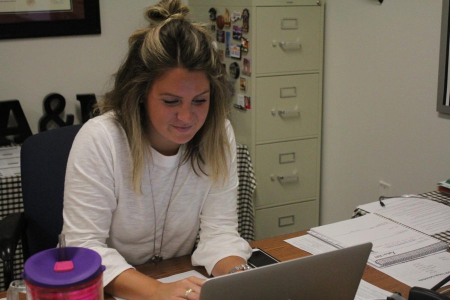 English 3 teacher Megan Stinson grins while working on her laptop. 