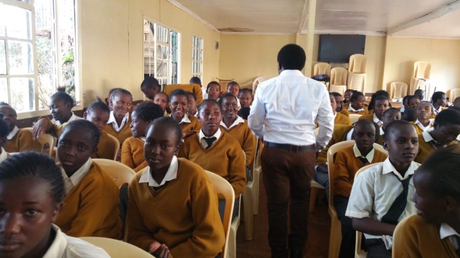Students at New Dawn Education Center in Nairobi, Kenya sit in rows as their teacher begins class. They all have uniforms which is included in tuition costs.