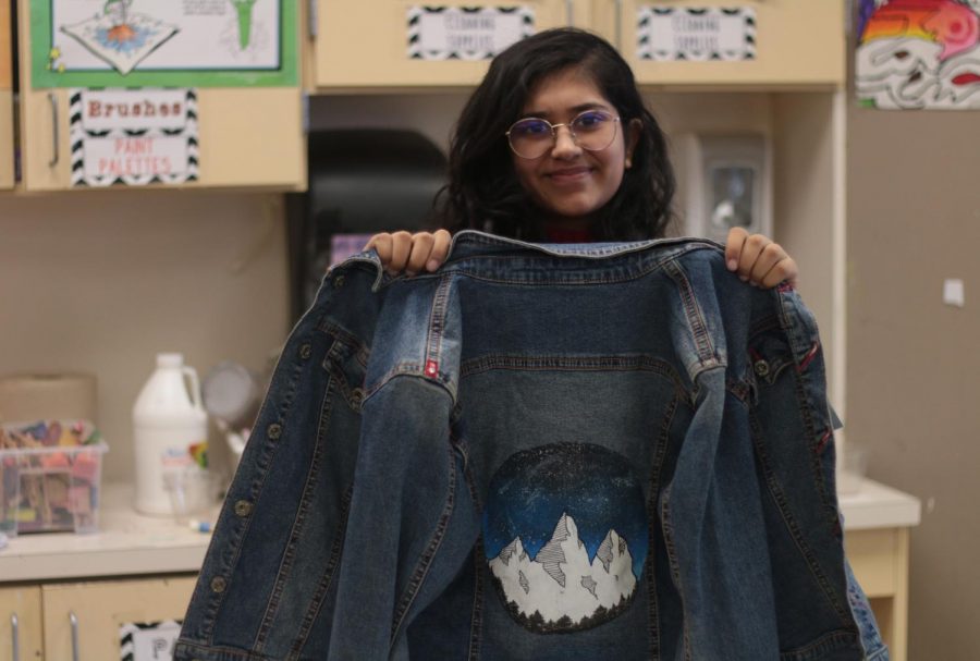 Sophomore Unaiza Khakoo poses with a jean jacket she painted. Khakoo will sell art pieces like this to raise money for an organization named Art From the Streets as a part of her Girl Scout gold award. “The gold award for Girl Scouts is the highest project you can do and the highest honor you can achieve,” Khakoo said. “In the project girl scouts are told to choose an issue they see in their community and find a way to combat it.”

