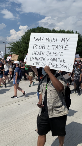 Man marches with sign that says 'Why must my people taste death before drinking from the cup of freedom?