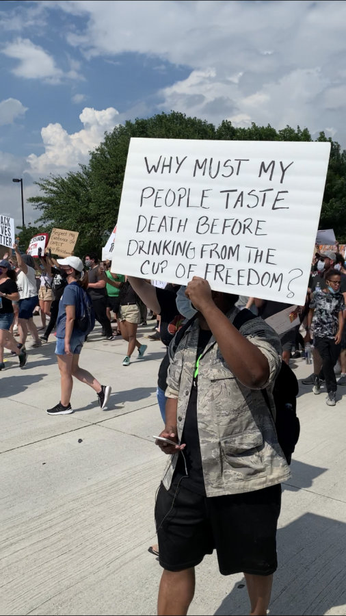 Man marches with sign that says Why must my people taste death before drinking from the cup of freedom?