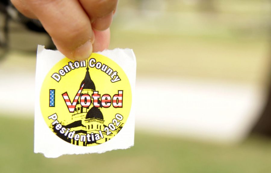 Voter Samina Ismail holds out her sticker that she received after voting at the Rosemeade Recreation Center. After scanning in their ballots, voters receive a sticker recognizing that they voted. 