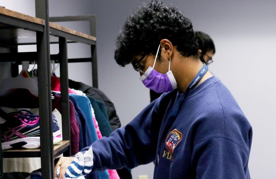 Senior Ali Niaz sets up donations for the clothing drive during third period on Dec. 4. Students are able to take clothes and food from the Hawk Pantry if needed.