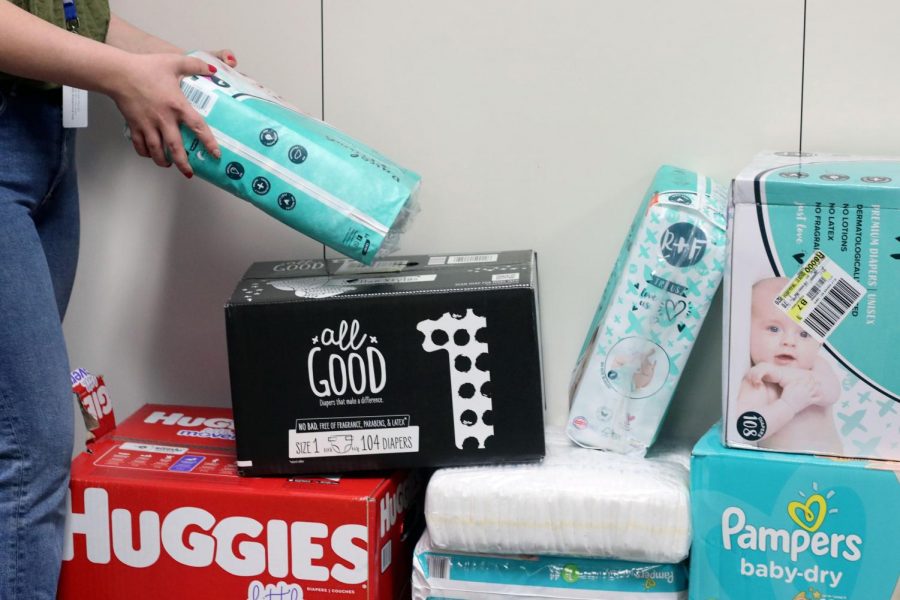 Senior Katlynn Fox donates a pack of diapers outside of 
 senior class sponsor Christina Shadow's room.