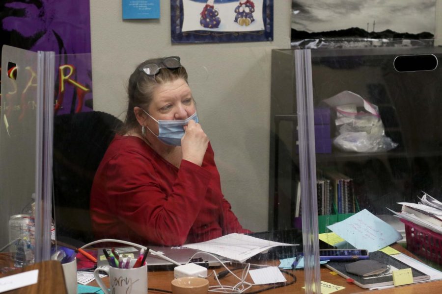 Becky Bertrand pulls up her mask while teaching her English II class behind a desk shield. 