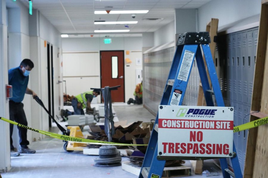 Construction workers remove debris and lay tile in the hallway that connects the 1300 and 1400 hallways. Construction around the school is expected to be complete by the end of the summer.
