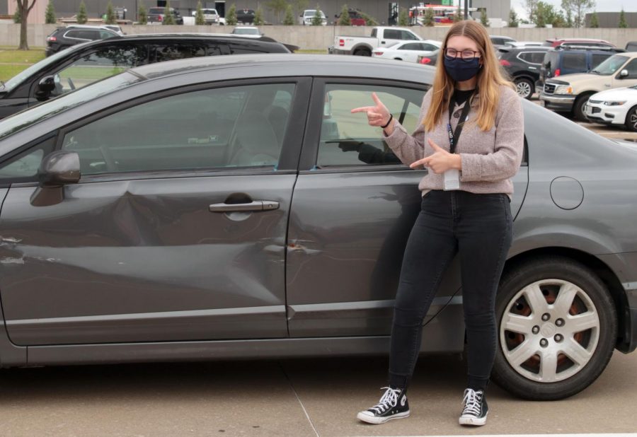 Senior Jacquelyn Burrer poses next to her car. The dent in her car was a result of an accident where she got T-boned on Marsh and Plano Parkway. 