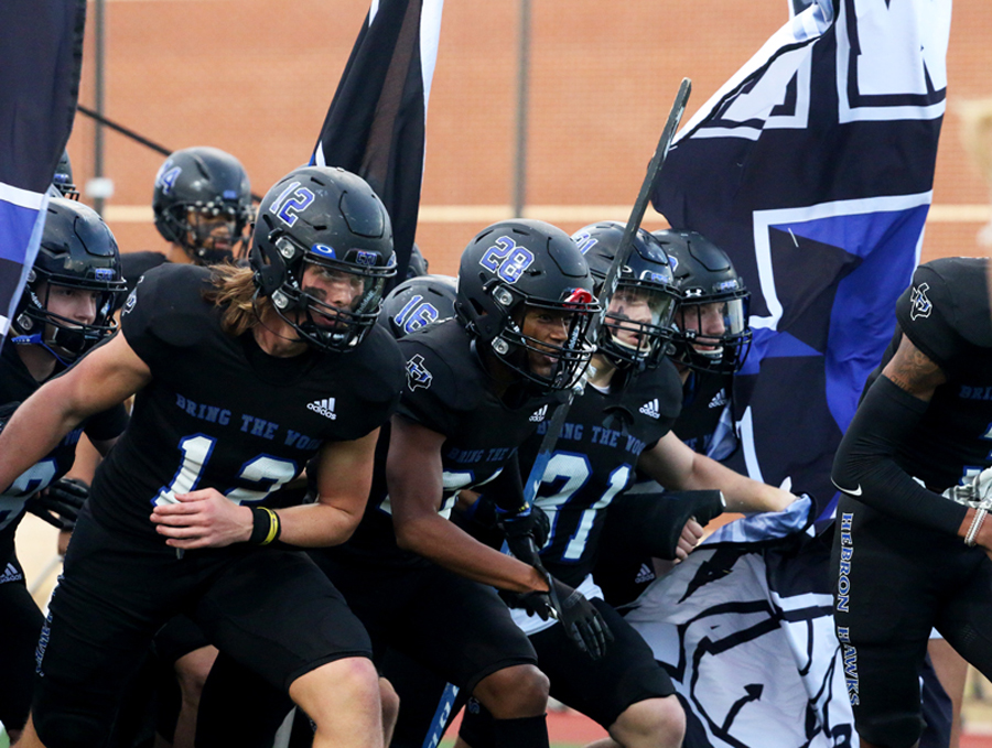 Tight end and middle linebacker Carter Brock and cornerback Travail Jones enter the field along with the rest of the team before the game begins. The football team runs in through the large inflatable Super-H at every game.