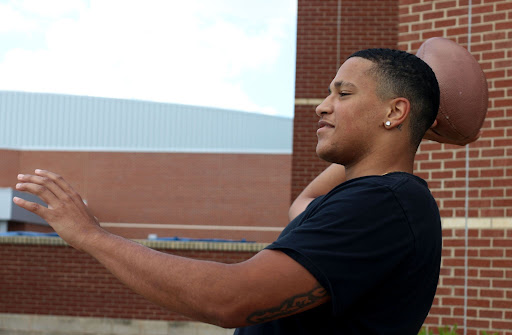 Senior Joe Onuwabhagbe throws a football outside. Onuwabhagbe has been on the football team since freshmen year and has committed to play D1 football.