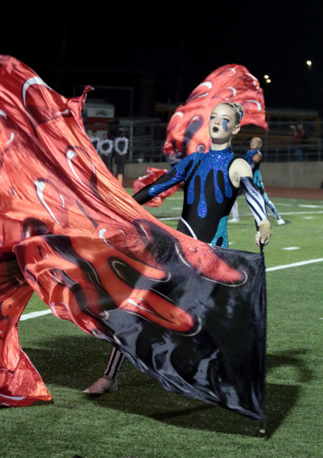 Sophomore Kylee Miller twirls two flags during the marching band halftime performance. The theme of this year’s marching show is is “Penstriped.”