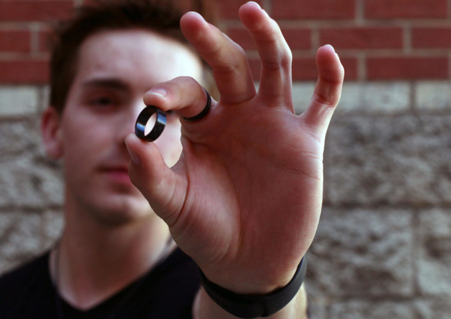 Senior Andrew George poses outside holding and wearing his handcrafted rings. George’s Instagram account for his business, @carboncrafted.acg, has photos of his rings that people can look at prior to placing an order. 