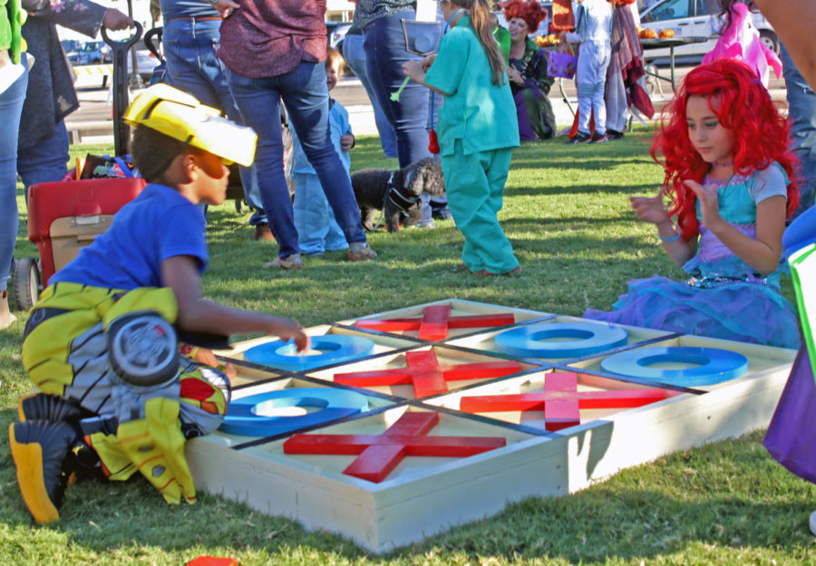 Two children play against each other on a giant tic-tac-toe board in the park. The event also included a costume contest, encouraging attendees to dress in their best Halloween attire. 
