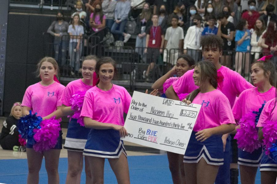 Cheer presents $2,235 check raised for ESL aide Naseem Hirji at Big Blue Goes Pink pep rally