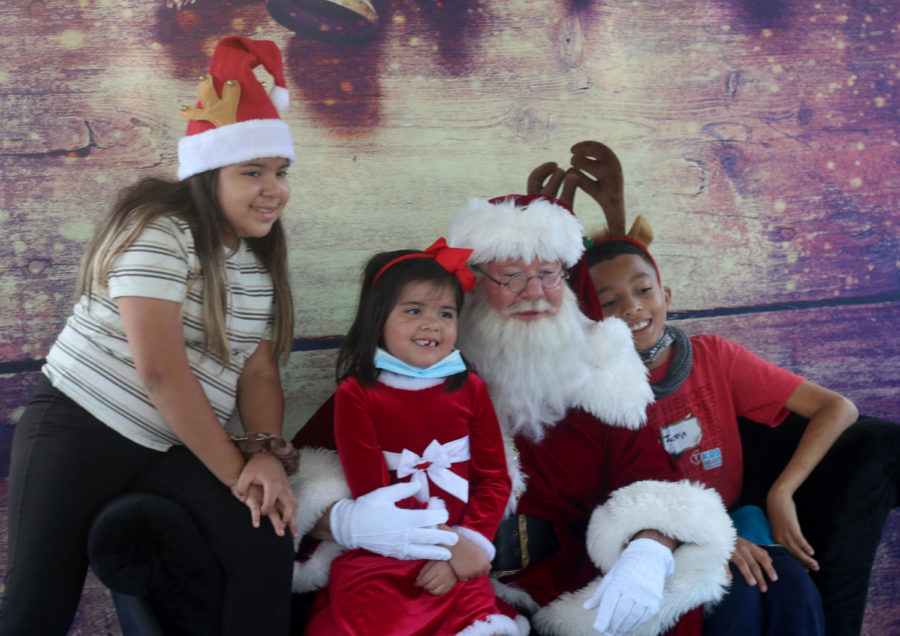 Children smile for a photo with Santa at the photo booth. Every year, children line up to take photos with Santa under the gazebo.