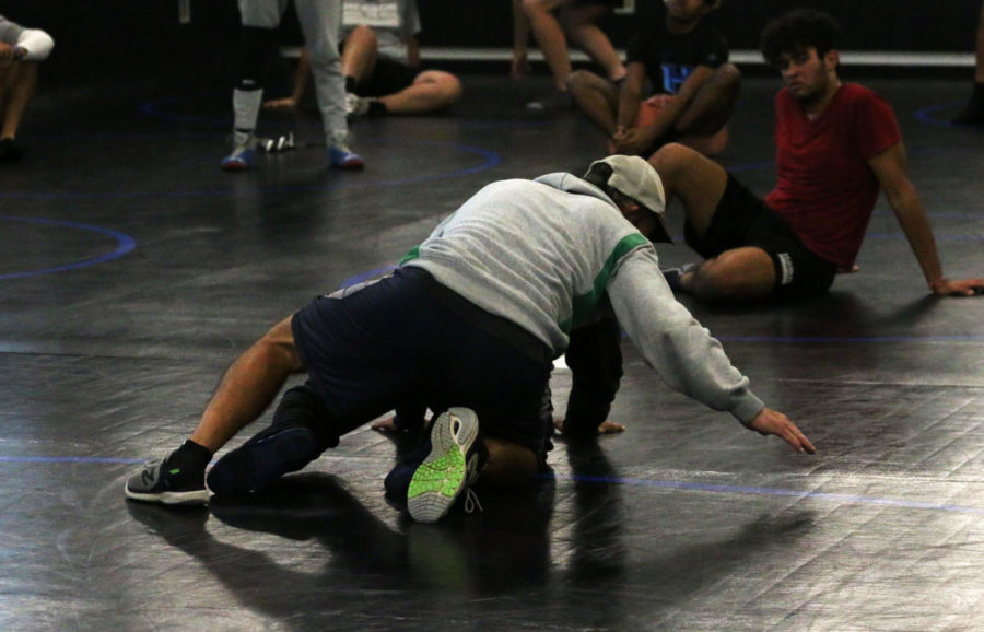 Wrestling coach David Rozanski demonstrates a move for some of the new members. The wrestling team holds practice every morning in their new mat room in the Hawk Activity Center.