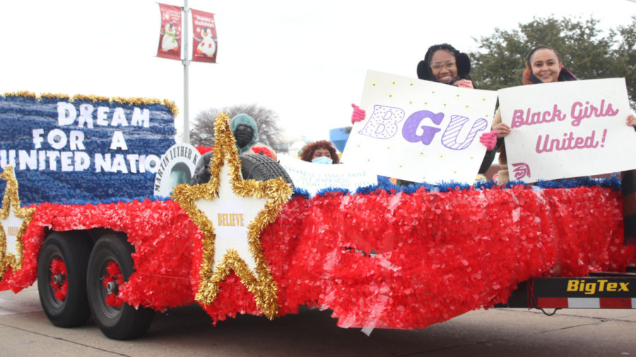 Black Girls United (BGU) members wave signs celebrating MLK Jr. day on their float. BGU has chapters across the nation and was created in 2017 by Ruby Clay, who desired to draw attention to issues facing Black American women.