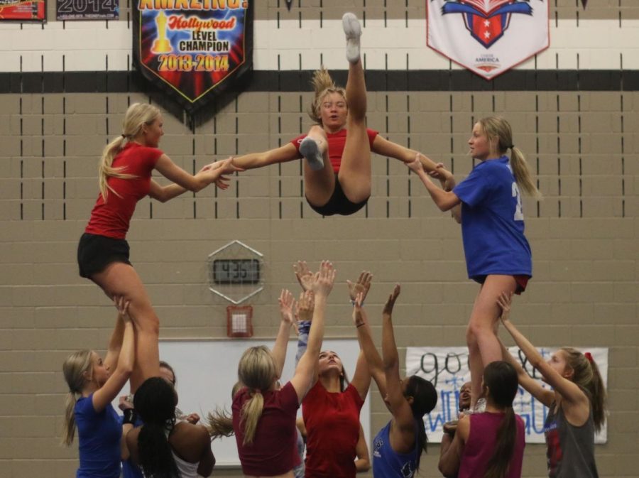 Junior Reece Hajek (left), sophomore Addison Carter (middle) and senior Avery Yabrough (right) are hoisted in the air by their bases during the pyramid section of their after-school practice on Jan. 20. 
