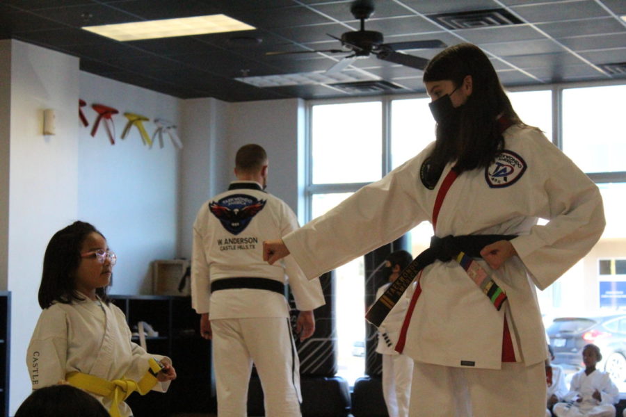 Freshman Chloe Klotzman teaches a yellow belt her form. Chloe is an instructor for Taekwondo America and works Tuesdays and Wednesdays after school. 