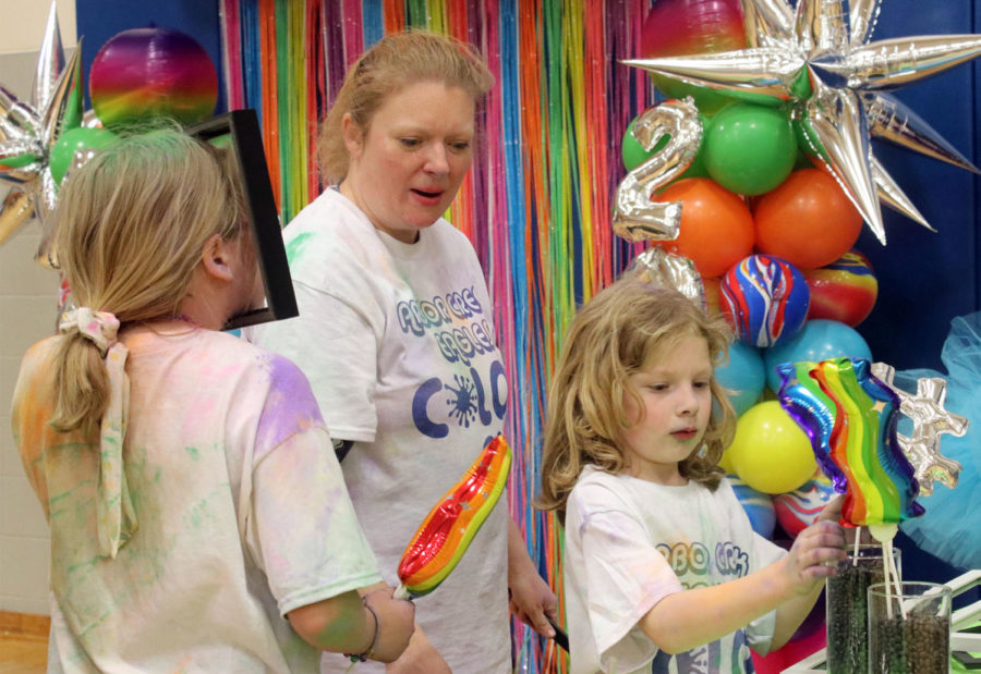 After completing a lap around the color run, a family prepares to take a photo at the gym’s photo booth. Before their picture, they selected props and outfits.