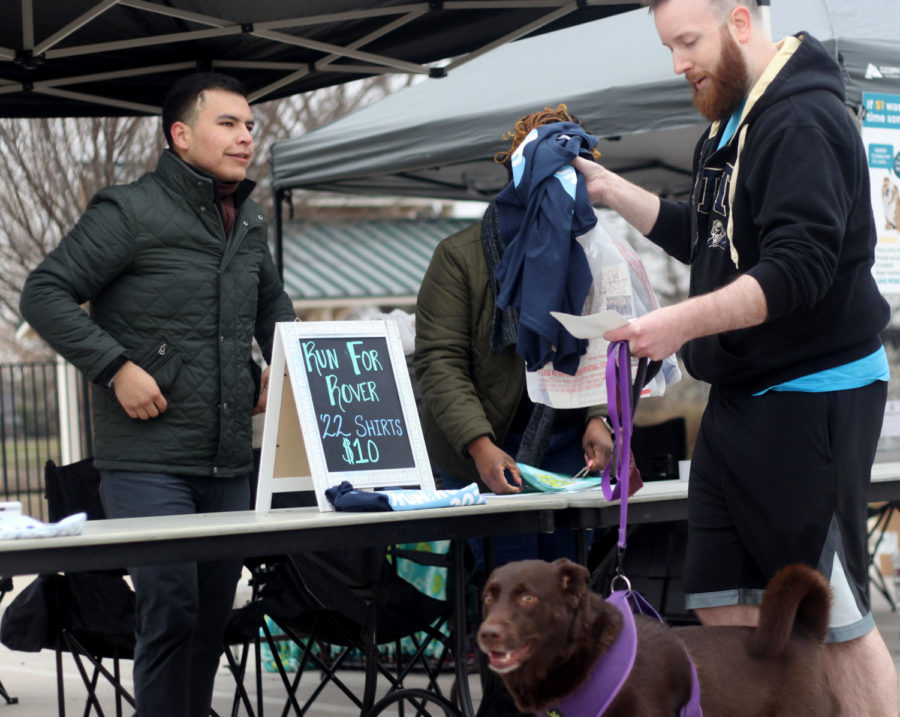Participant Austin and his dog, Tessie, pick up their early registration rewards and his number for the run. All of the 5k runners who signed up prior to Feb. 22 were given a race T-shirt, bag and a timing chip.