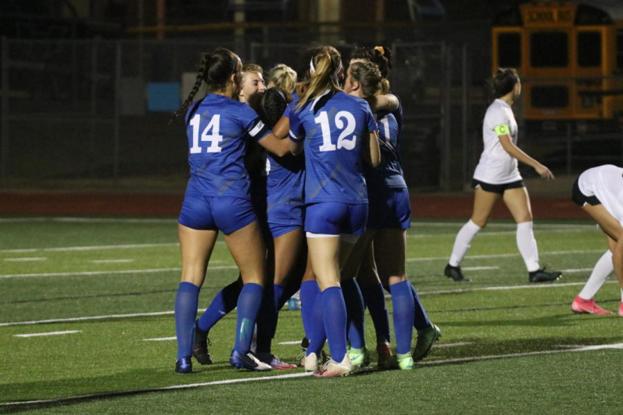 The girls soccer team embraces during a home game against Lewisville on Feb. 15. The team beat Lewisville by a score of 7-0.