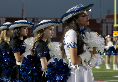 First lieutenat Isabel Amell puts her hand on her heart as the national anthem is sung at a football game. The wings have been preparing dances for the spring show since football season.