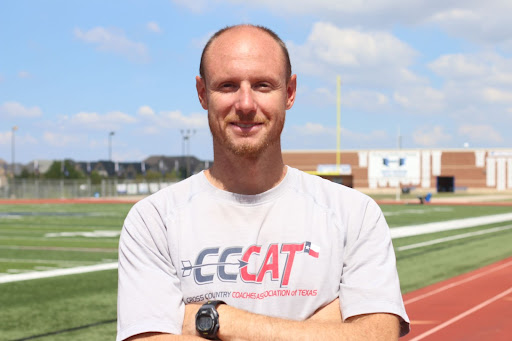 Coach Chance Edwards poses in front of the track at the Hawk Stadium.