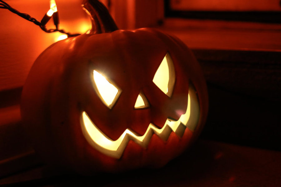 A lit jack-o-lantern sits on a porch in preparation for Halloween
