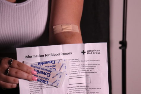 Opinion editor and social media manager Madeline Rivera holds a Red Cross blood donor form next to the arm she donated with. After her fathers life was saved by a blood transfusion, Rivera was motivated to participate in her schools blood drive to give back.