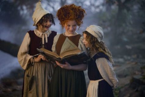 The young Sanderson sisters read their newly-gifted spell book in the Forbidden Woods. The movie stars Nina Kitchen as young Mary, Taylor Henderson as young Winifred and Juju Brener as young Sarah.