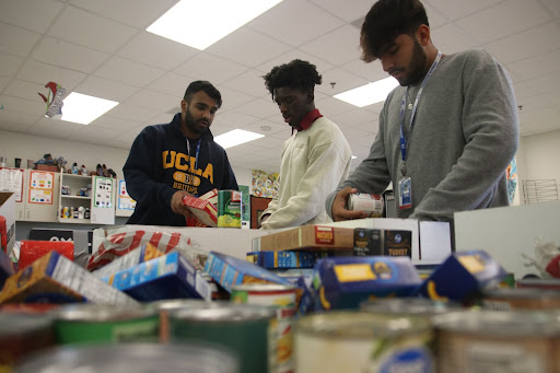 Student Council Treasurer Asil Mithani, senior Emeka Ohumaegbulem and Student Council Vice President Rahil Tanvir sort through donated cans and boxes of food. 