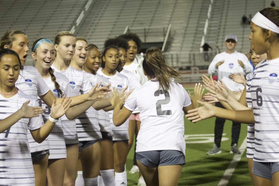 Junior Tati Diaz high fives her teammates. At the start of every soccer game, each player is individually introduced by the announcers.