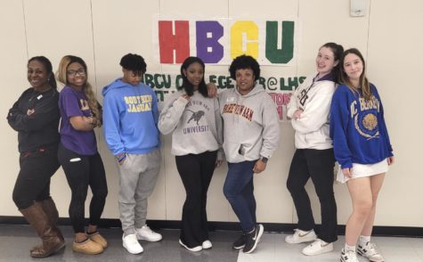 Black Student Union sponsor Alicia Hensley, juniors Analjah Ratliff and Sarah Dawson, senior Xavier Champ, AVID teacher Erica Randle and seniors Leah Dean and Emily Olive pose in front of an HBCU college fair poster. They all wore college t-shirts and hoodies for college day dress up day on Feb. 15. 