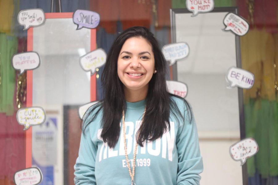 Counseling and mental health teacher Jacqueline Rans smiles in front of the class display featuring two mirrors with positive affirmations attached to them. The display, made by her students, is designed for people walking in the halls to see their reflection and appreciate themselves.