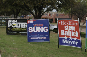 Signs from Carrollton’s mayor candidates, Adam Polter, Young Sung  and Steve Babick, are displayed on the intersection of Hebron Parkway and Old Denton Road. 
