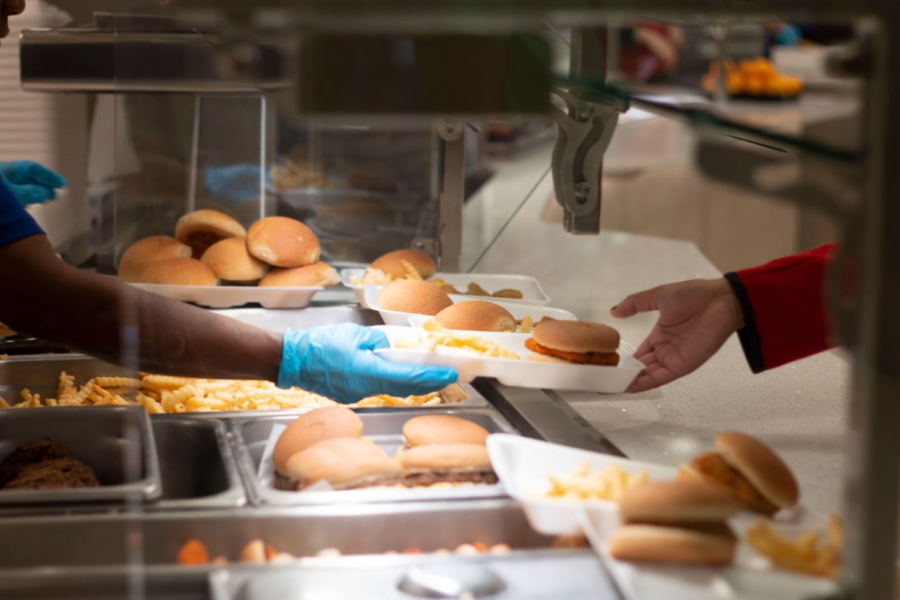 The lunch ladies set up trays and pass them out to students during D lunch. The lunch ladies make food throughout the day and then set up trays before students line up.