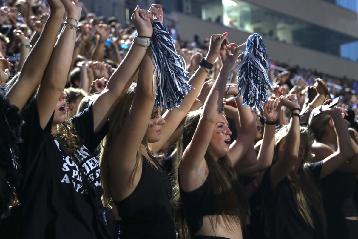 The student section links pinkies before a kick off. The student section theme for this game was “black out.”